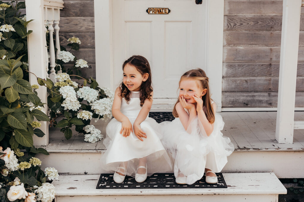two little girls sit on steps of a cottage