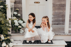 two little girls sit on steps of a cottage