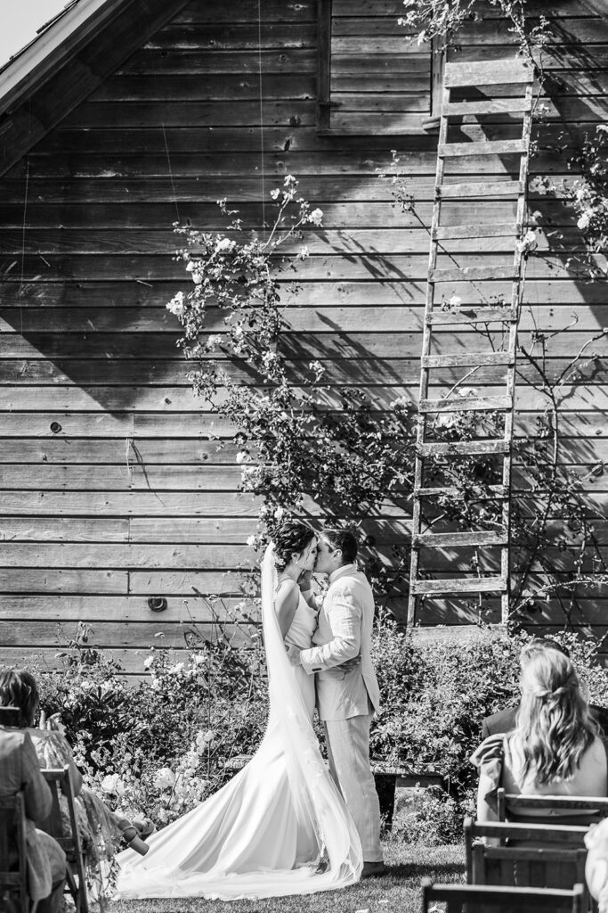bride and groom kiss in rose garden
