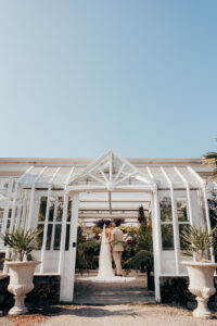 bride and groom stand in greenhouse