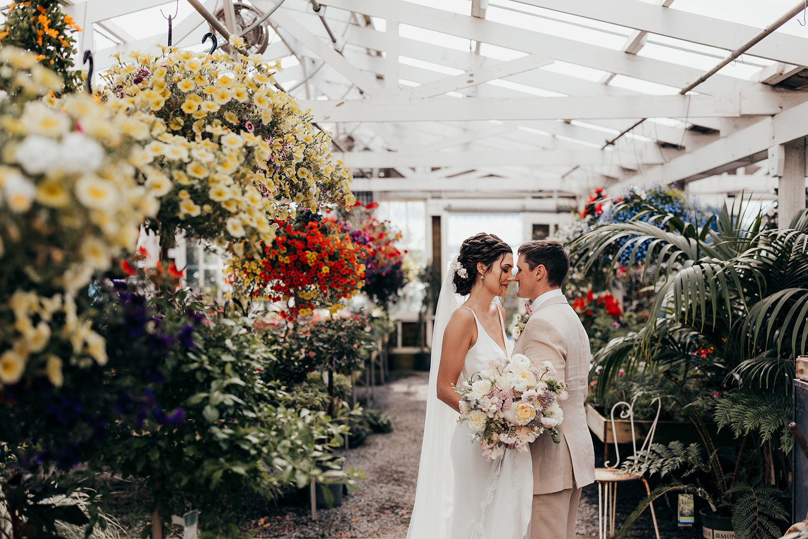 bride and groom kiss in greenhouse