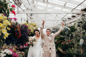 bride and groom cheer in greenhouse