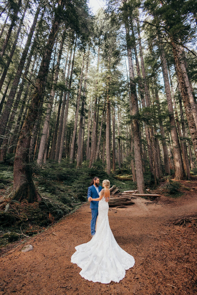 bride and groom stand in  forest at Mt Rainier