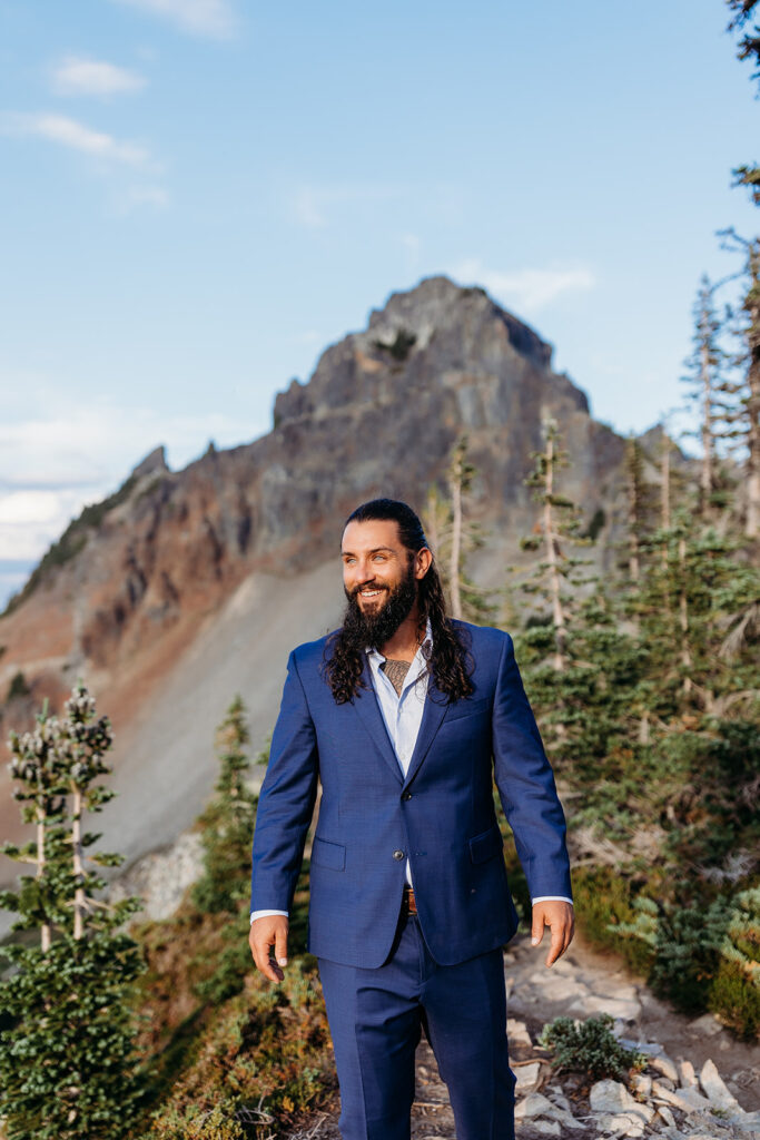 groom poses in blue suit on mt rainier