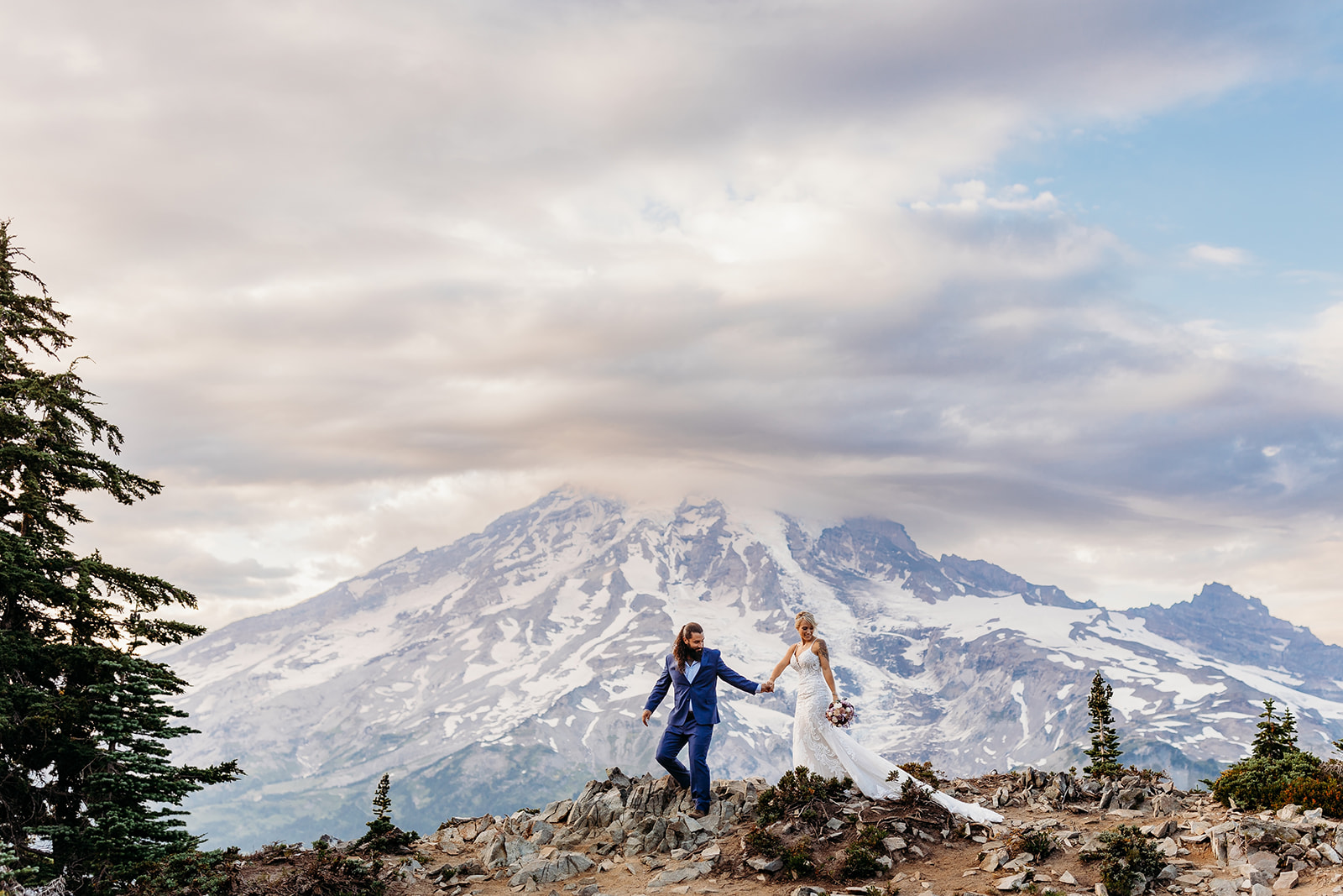 bride and groom walk along ridge at mt rainier