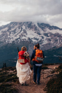 bride and groom wear backpacks with "just married" signs on them